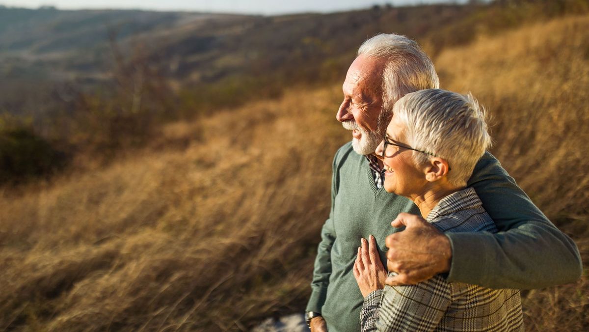 &Auml;lteres P&auml;rchen steht auf einem H&uuml;gel und schaut fr&ouml;hlich in die Ferne
