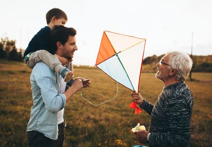 Drei Generationen haben Spaß beim Drachensteigenlassen im Freien