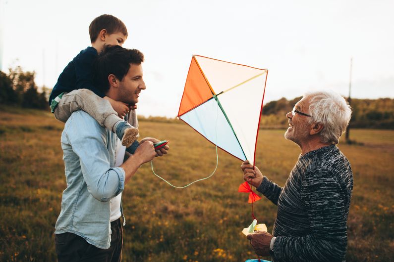 Drei Generationen haben Spaß beim Drachensteigenlassen im Freien